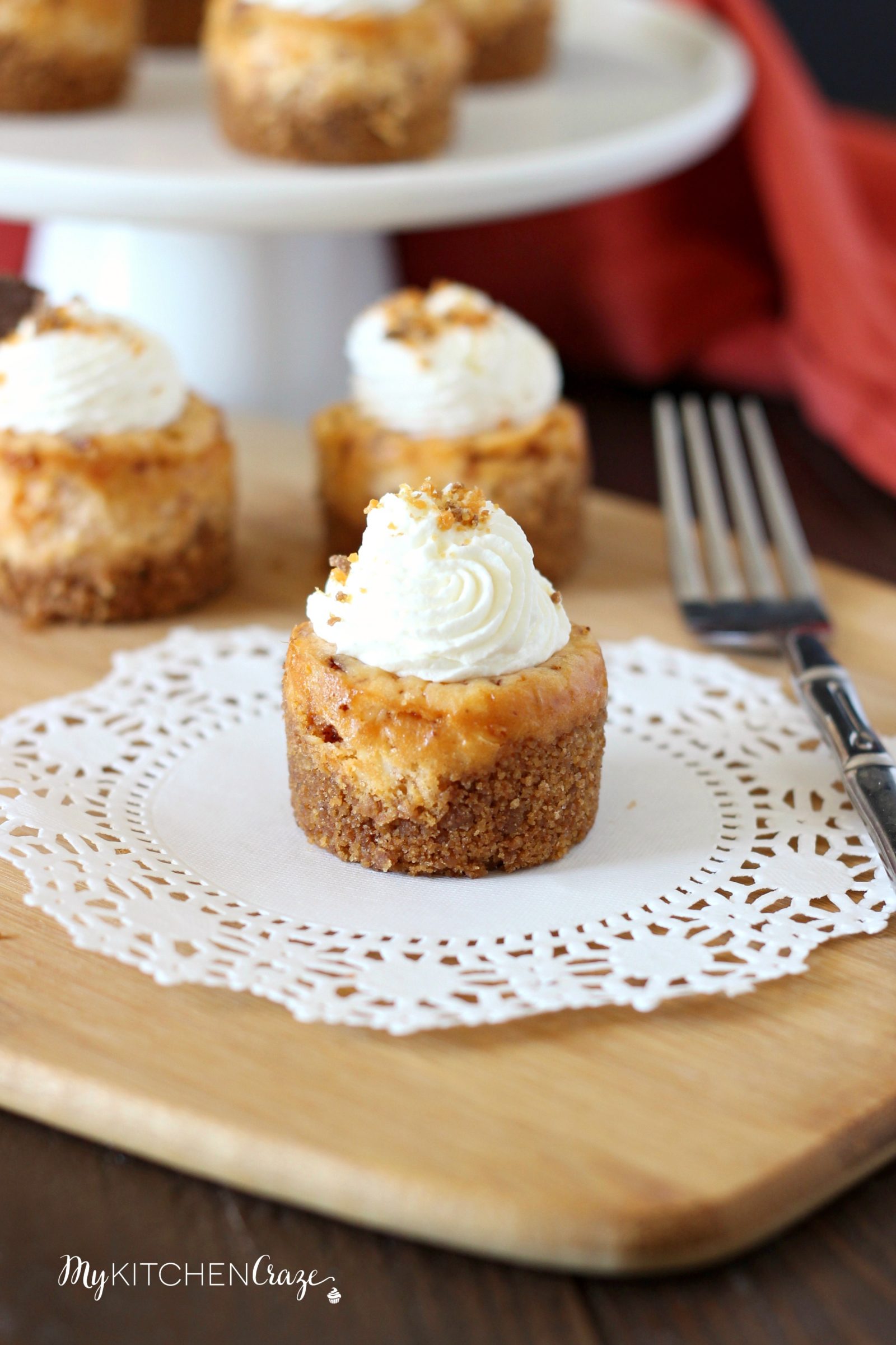 Mini Butterfinger Cheesecakes ~ mykitchencraze.com ~ Delicious cheesecakes swirled with butterfingers candies and topped with whipped cream! Yum!