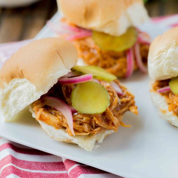 BBQ Pulled Chicken Sliders are packed with delicious flavor! The chicken is slow cooked with Barbecue sauce then shredded or 'pulled' and piled on top of slider rolls. Perfect for a busy night or a fun gathering!